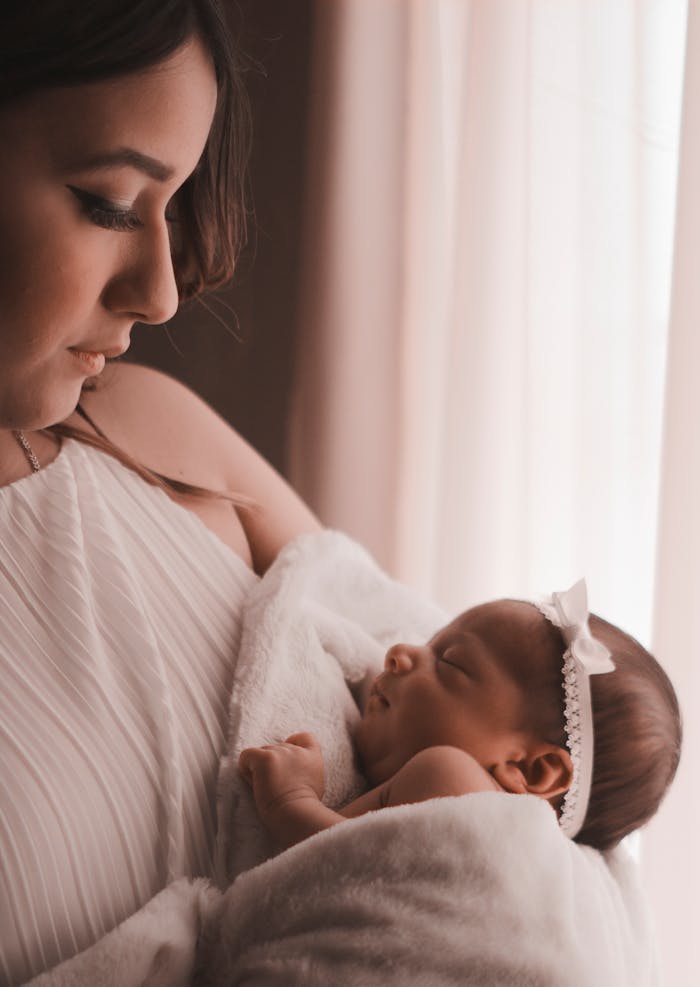 pexels photo 3398675 Tender moment of a mother holding her newborn child by a window, capturing love and warmth.