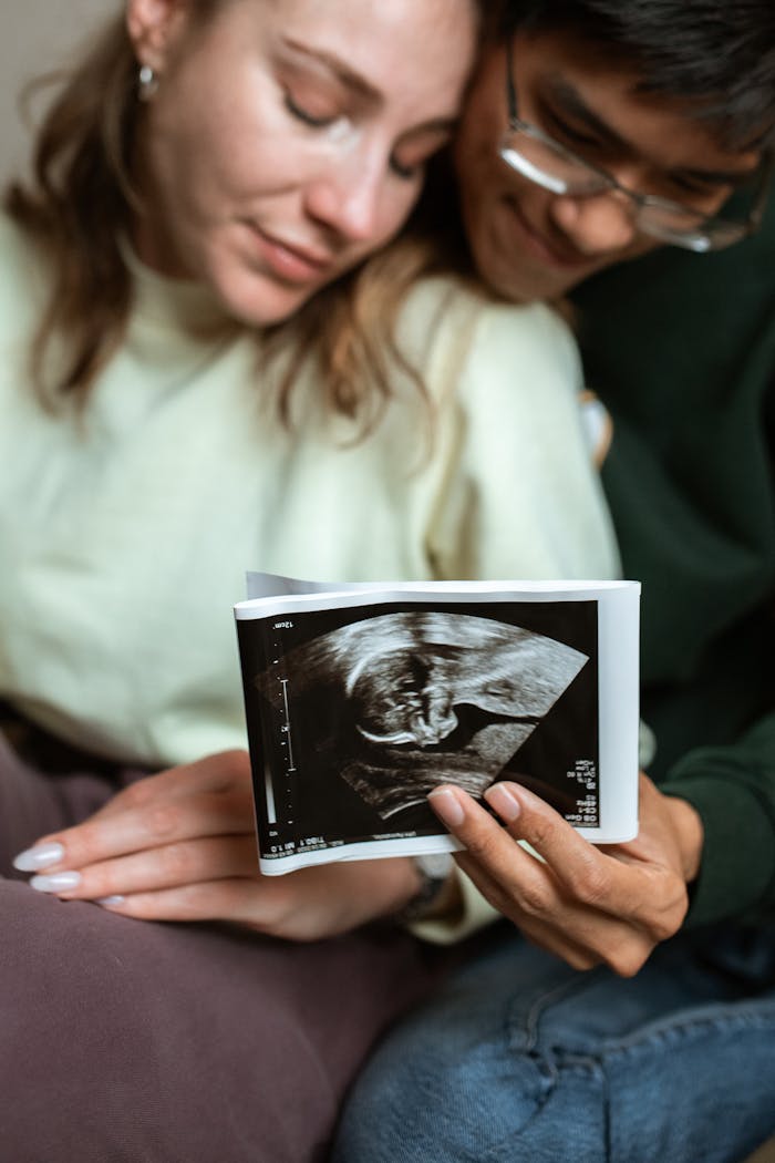 Home A couple lovingly holds an ultrasound photo, celebrating pregnancy indoors.